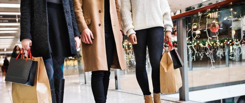 Three people christmas shopping in a mall content