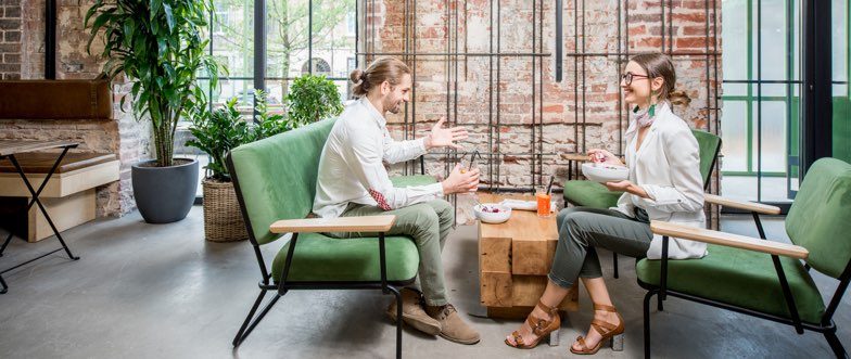 Two people talking while sitting on green chairs content