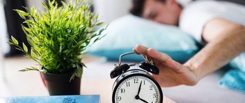 Man hitting pause on alarm clock content