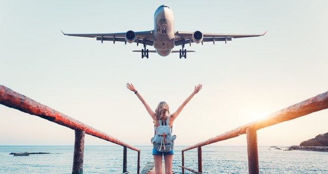 Woman on pier with plane about to fly over article image content