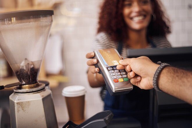 Small business owner holds up Eftpos machine for a 'tap and go' transaction