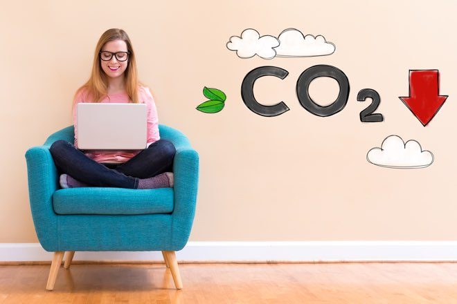 Woman sitting on an armchair, looking up green personal loans on a laptop.