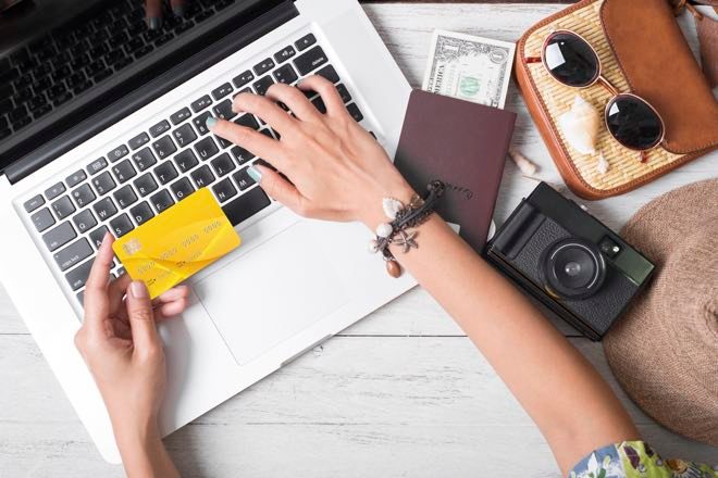Mujer bloqueando un tipo de cambio extranjero en una tarjeta de viaje prepaga usando su computadora portátil