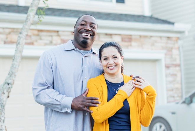 Landlords standing out the front of their investment property after securing it with landlord insurance.