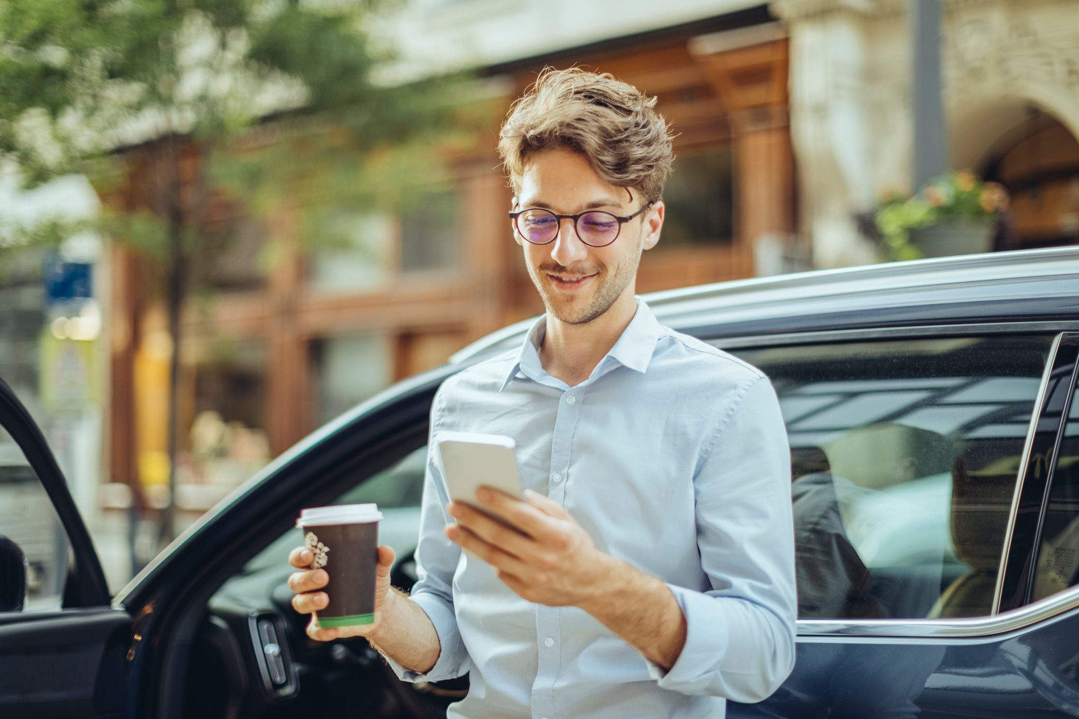 man looking at bank account on phone with coffee