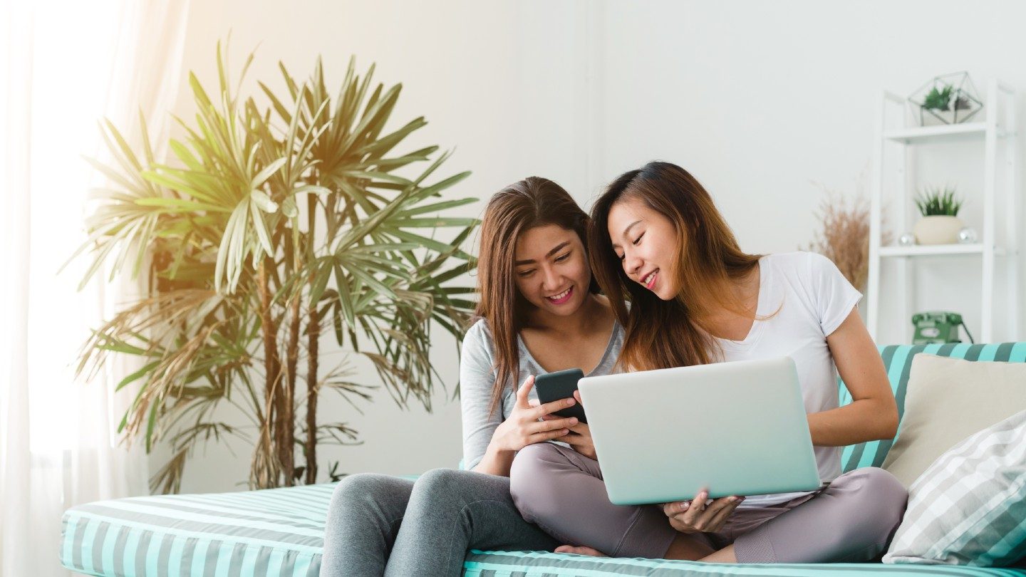 women on lounge happy using phone and laptop