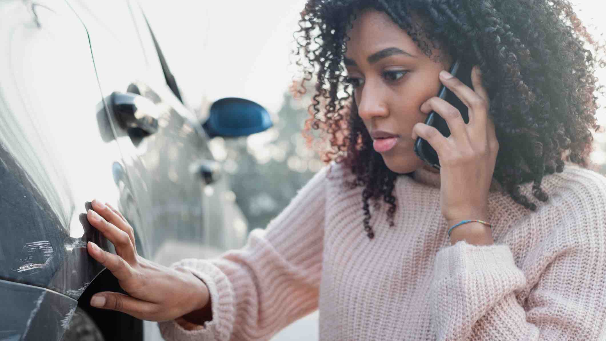Woman looking at car with scratches after getting in at fault car accident without insurance.