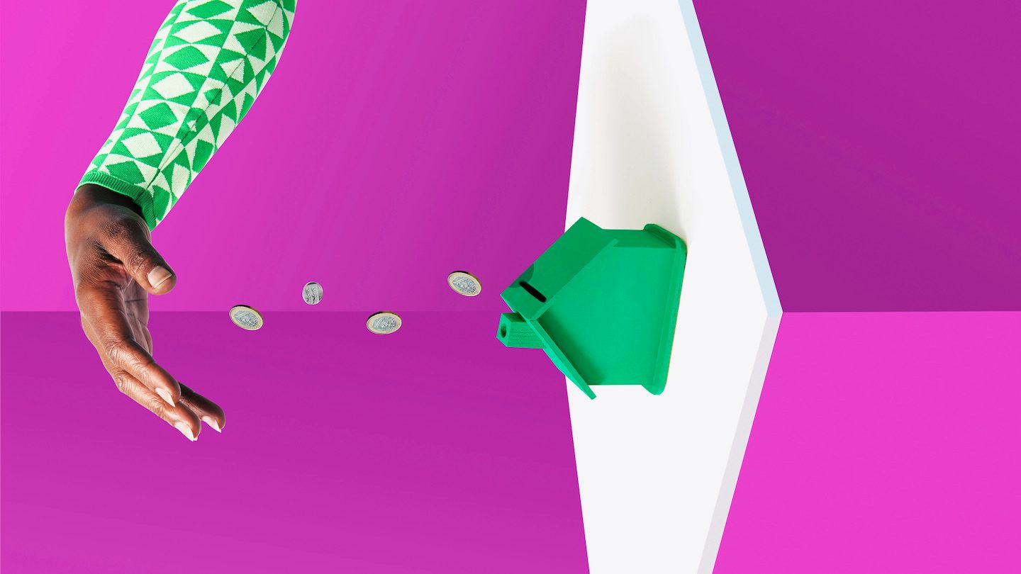 A hand pours coins into a green model house