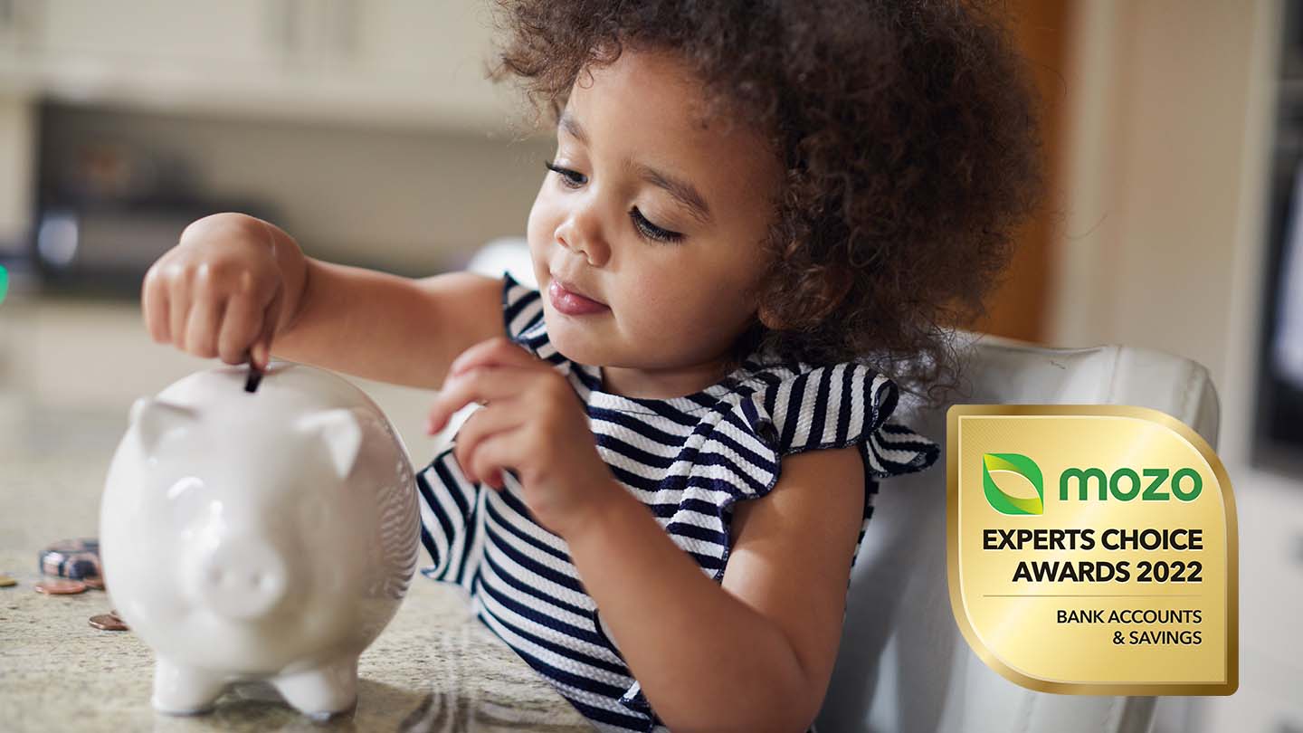 little girl putting money in a piggy bank for her mozo expert choice award winner kids savings account