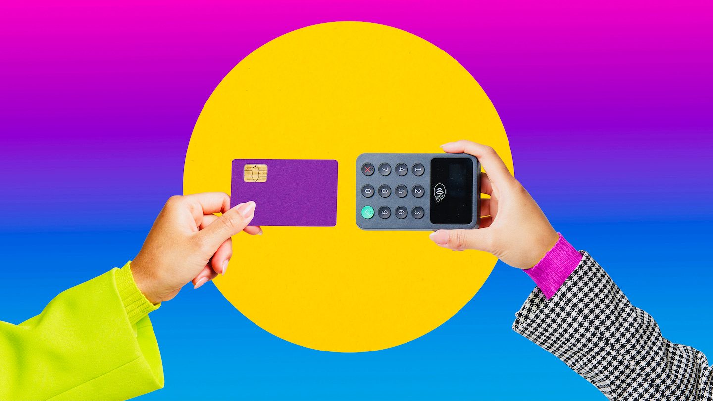 A hand scans a debit card on a card reader.