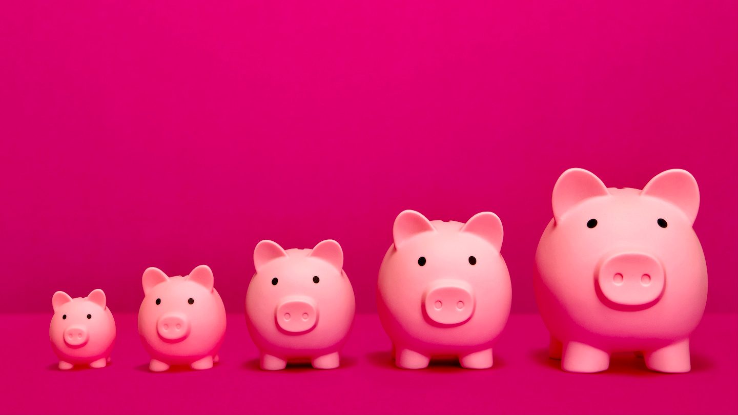 A row of pink piggy banks of increasing size.