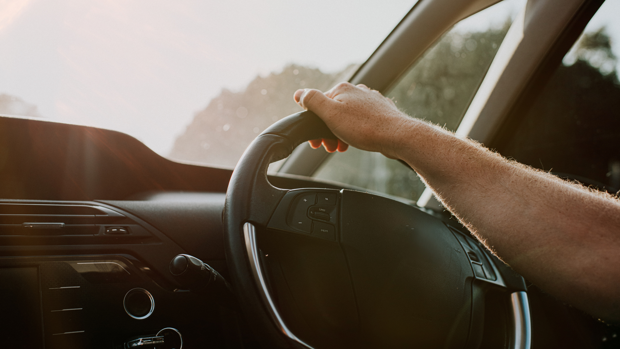 A hand rests comfortably on a steering wheel.