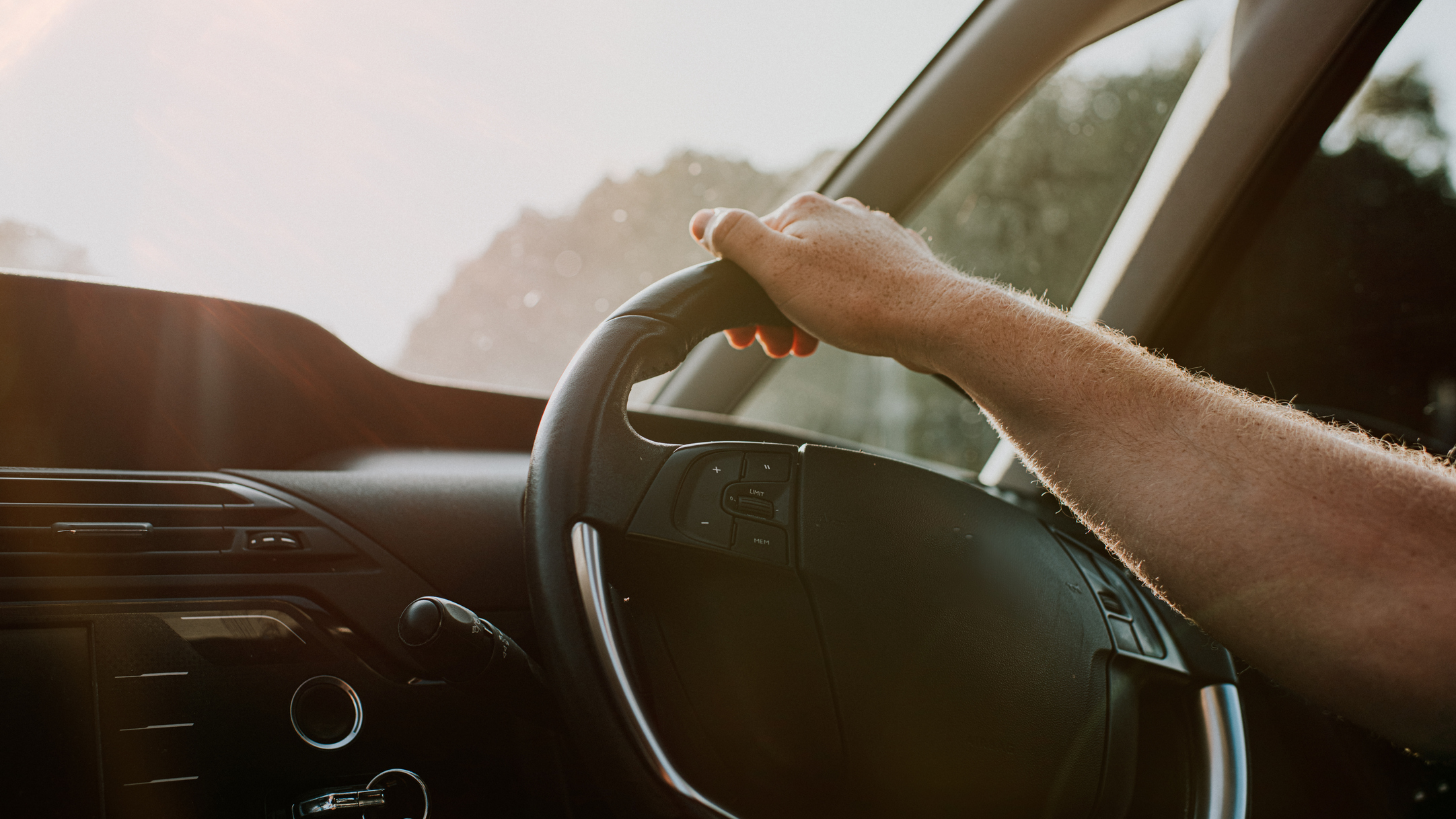 A hand rests comfortably on a steering wheel. 