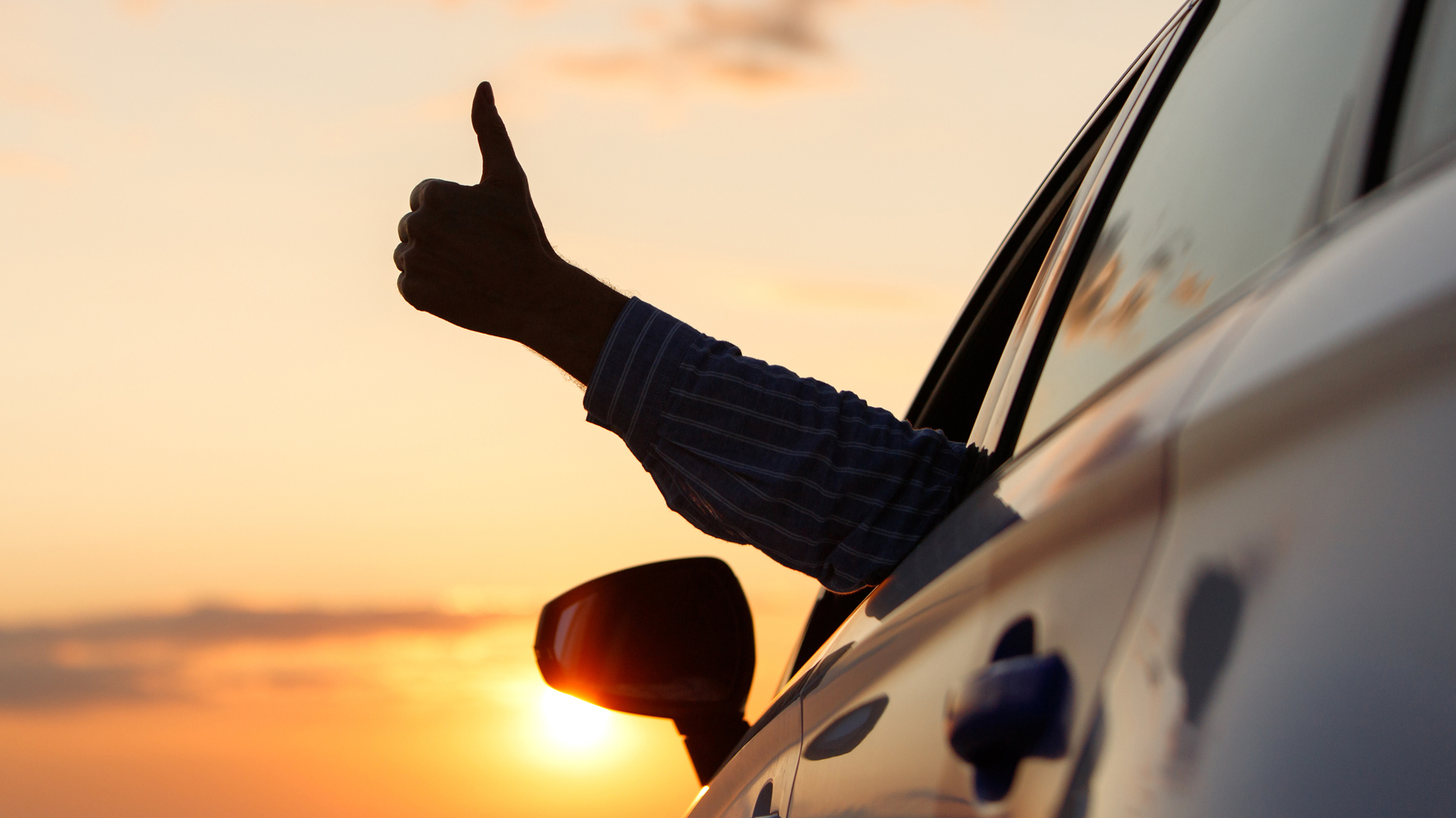 A person with their thumbs up out of a passenger door window.