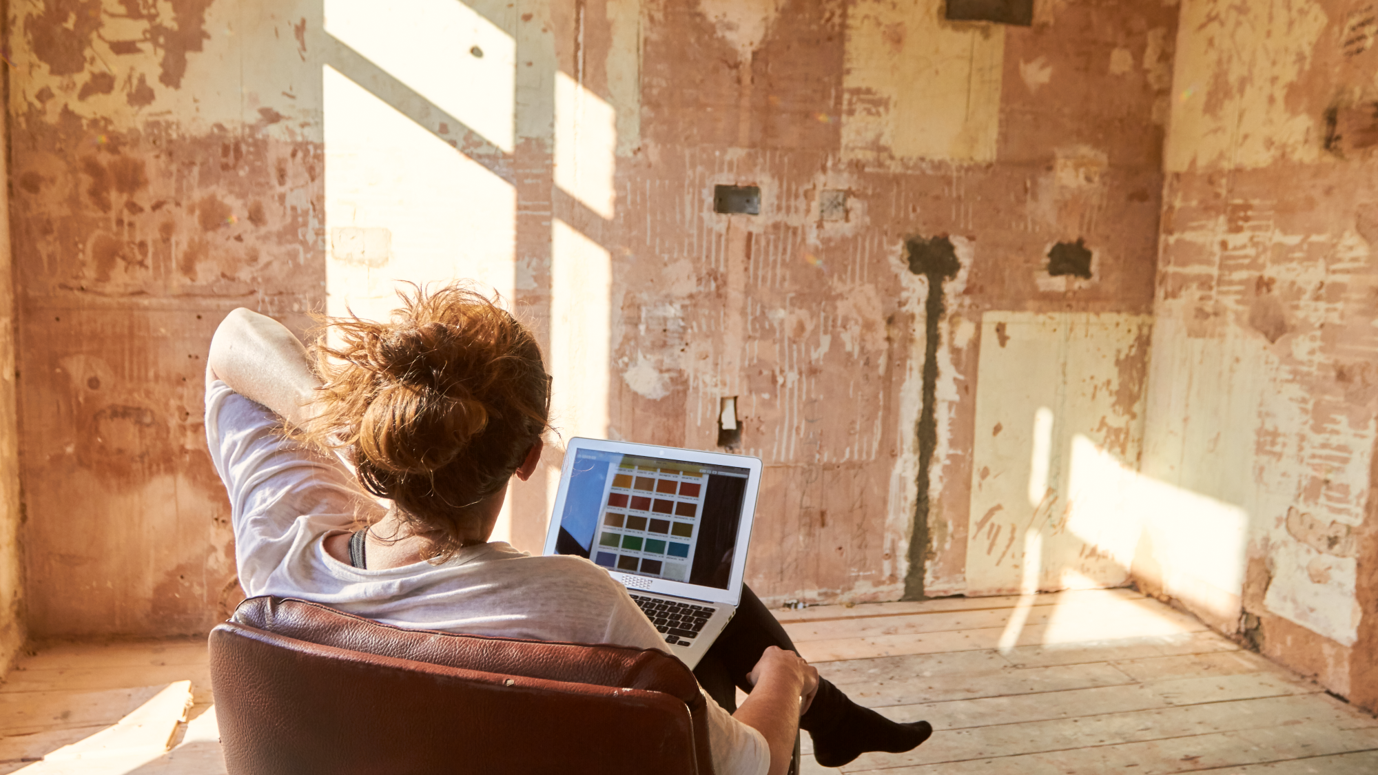 Woman looks at a colour palette on her computer screen and debates the right colour for the room