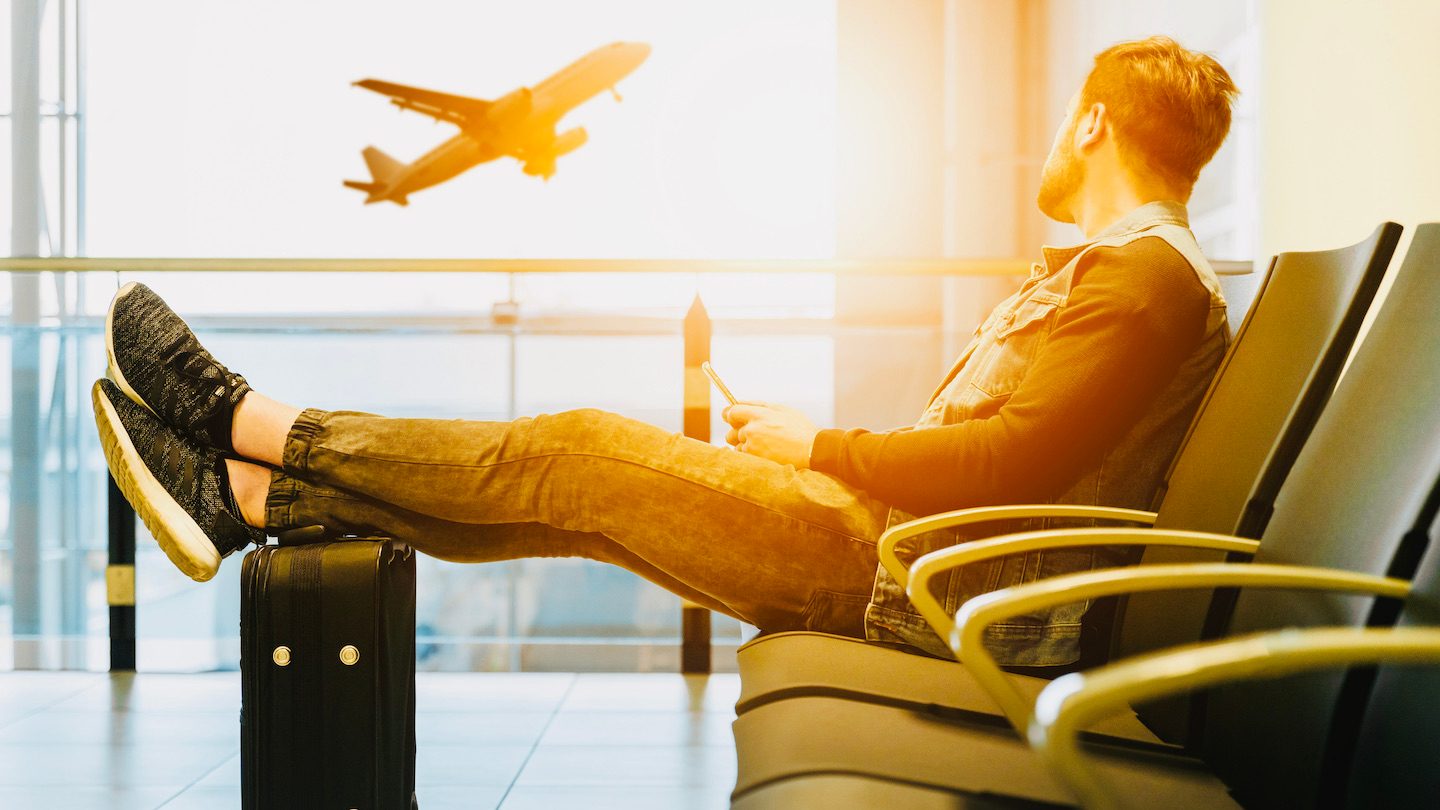 A man relaxes at the airport while watching a plan take off.