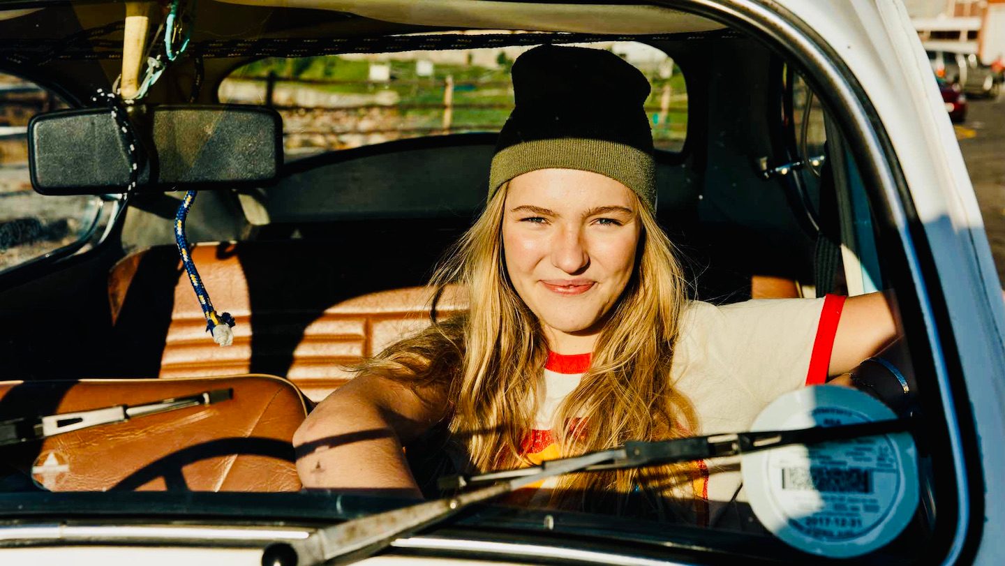 Person smiling in older car, with cheap car insurance