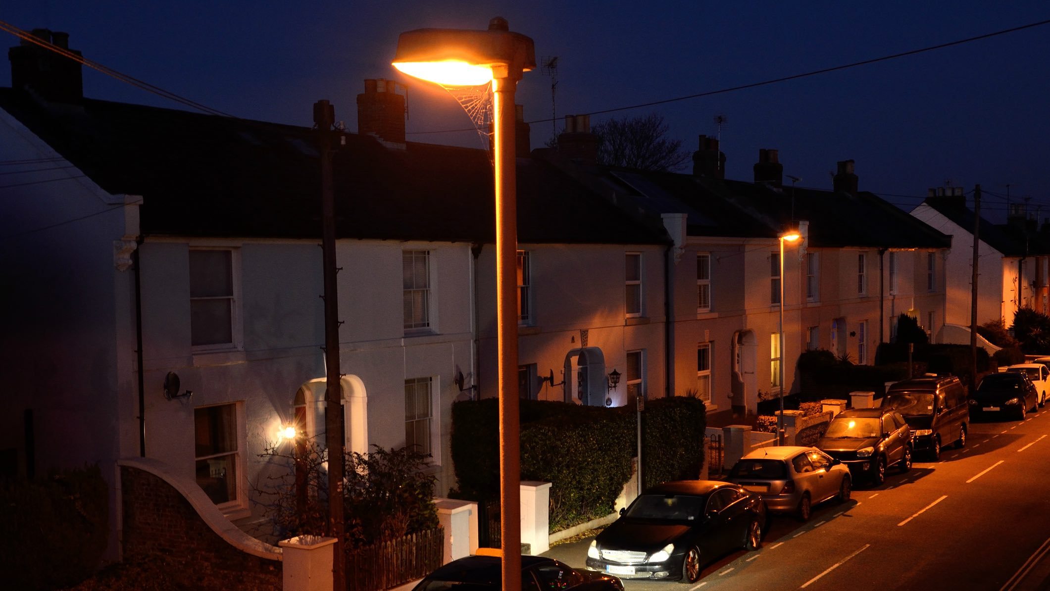Cars parked on a suburban street at night which might require fire and theft car insurance.