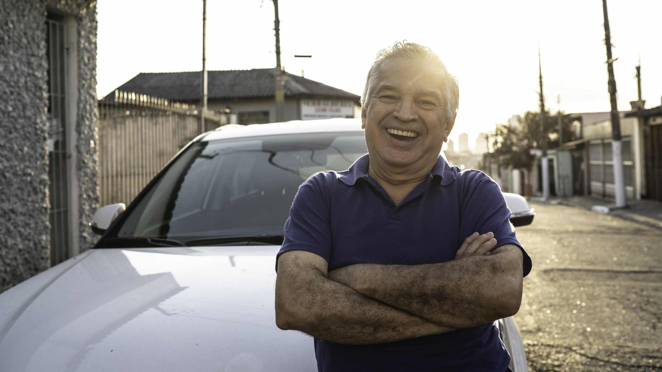 Man smiling in front of car with insurance