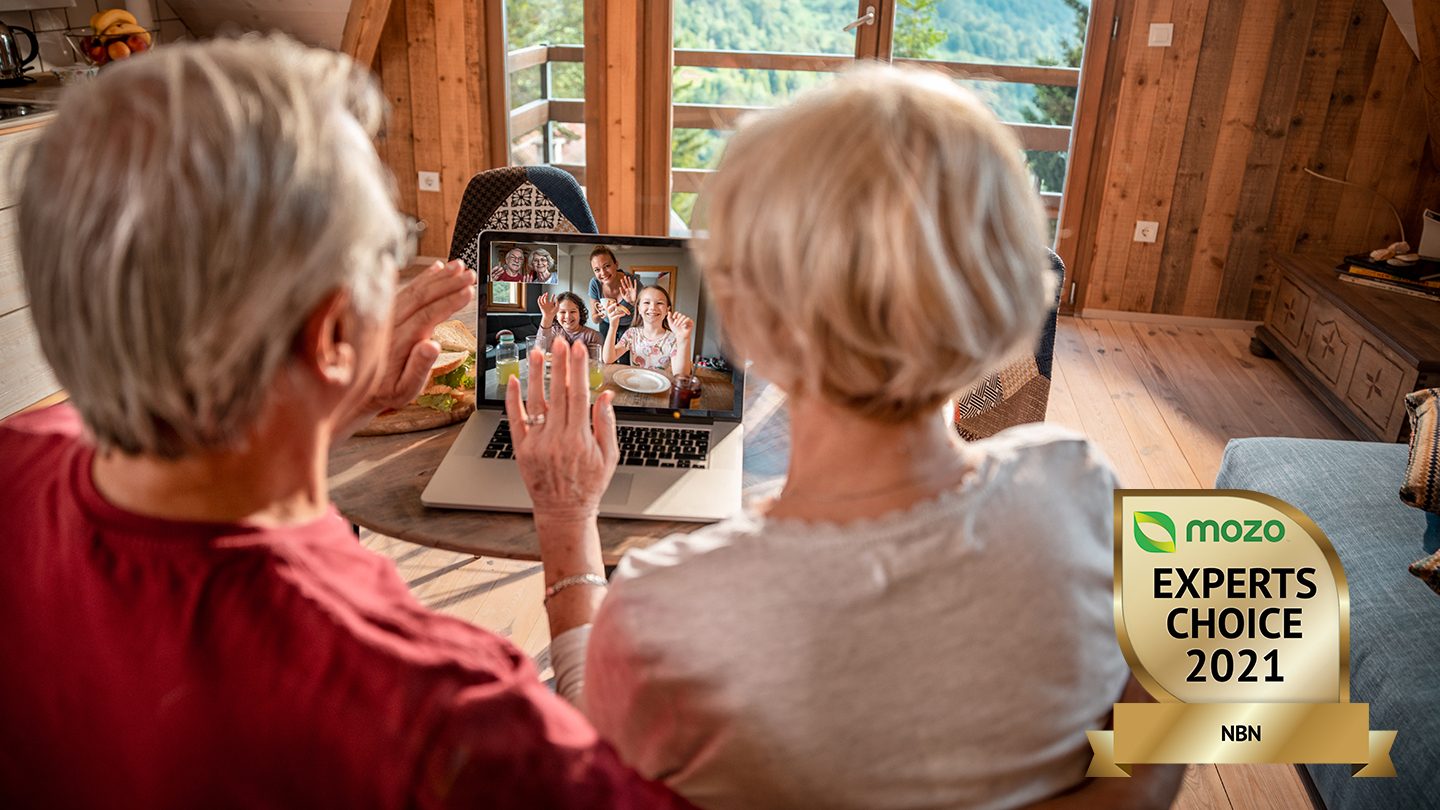 Older man and woman video chat with family on laptop.