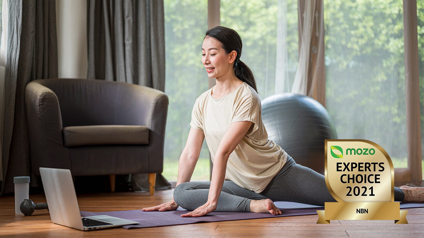 Woman follows yoga video on laptop.