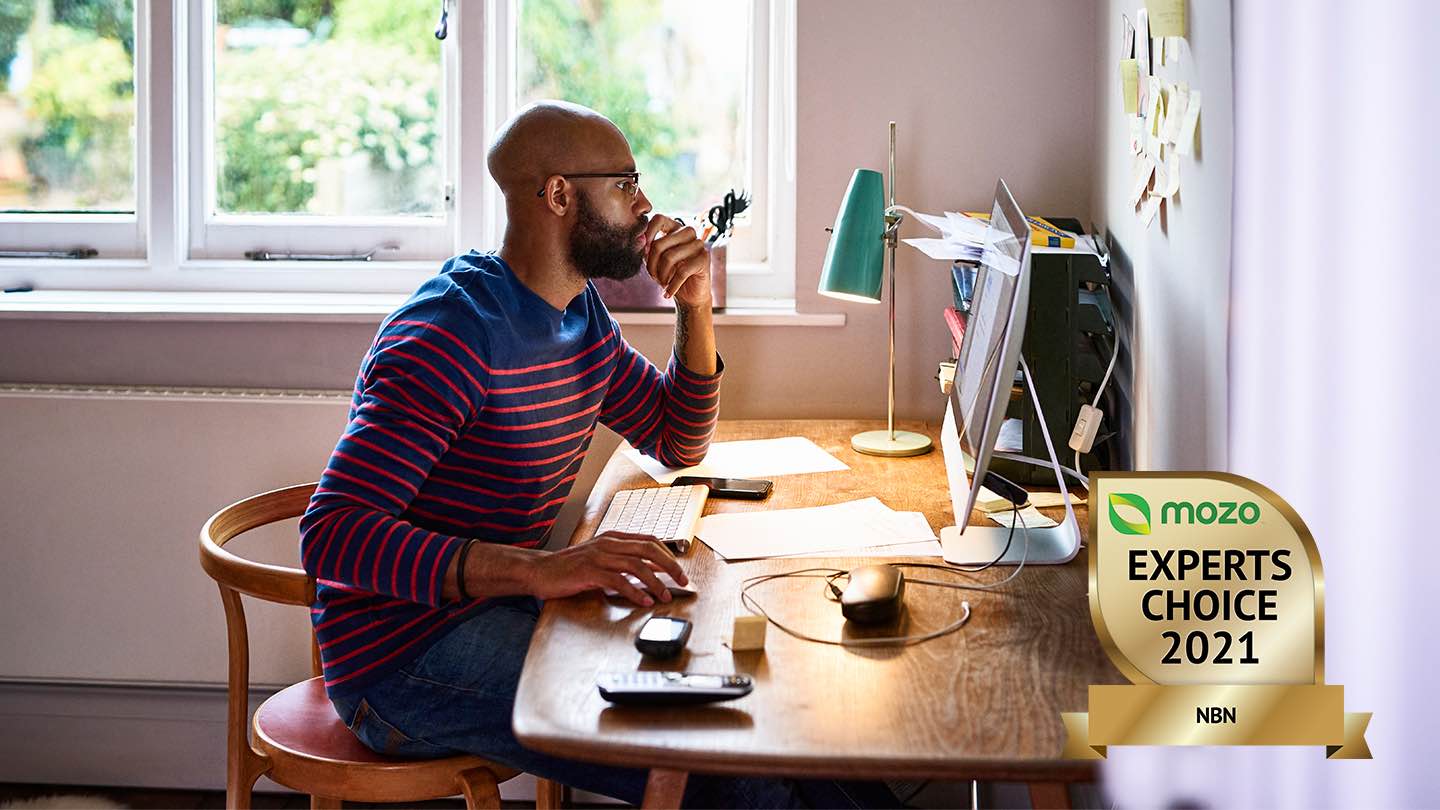 Man sits at desk, in front of computer.